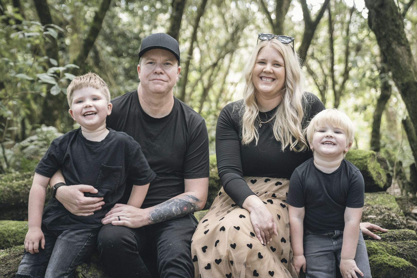 Paul Warren with his wife Emma and their two sons, sitting on a log in bushland near Melbourne.